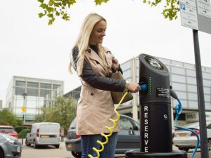 Woman using EV charger in car park