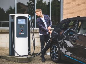 Man charging electric vehicle with Chargemaster station